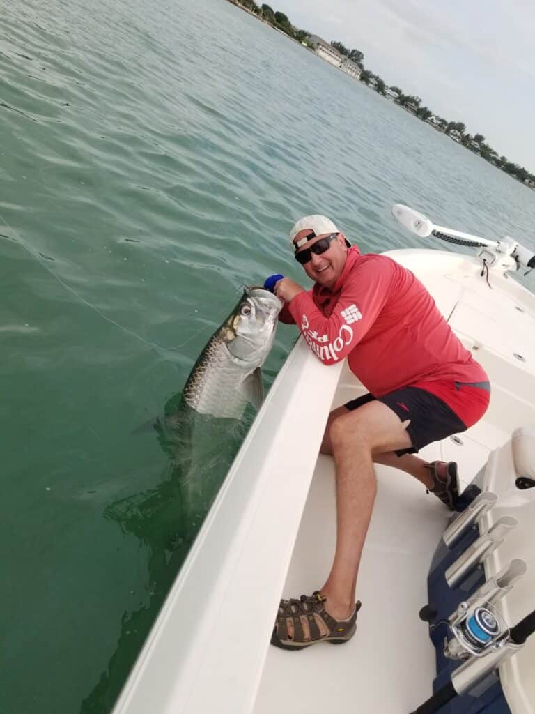 Angler holds a tarpon alongside a boat in the Boca Grande area